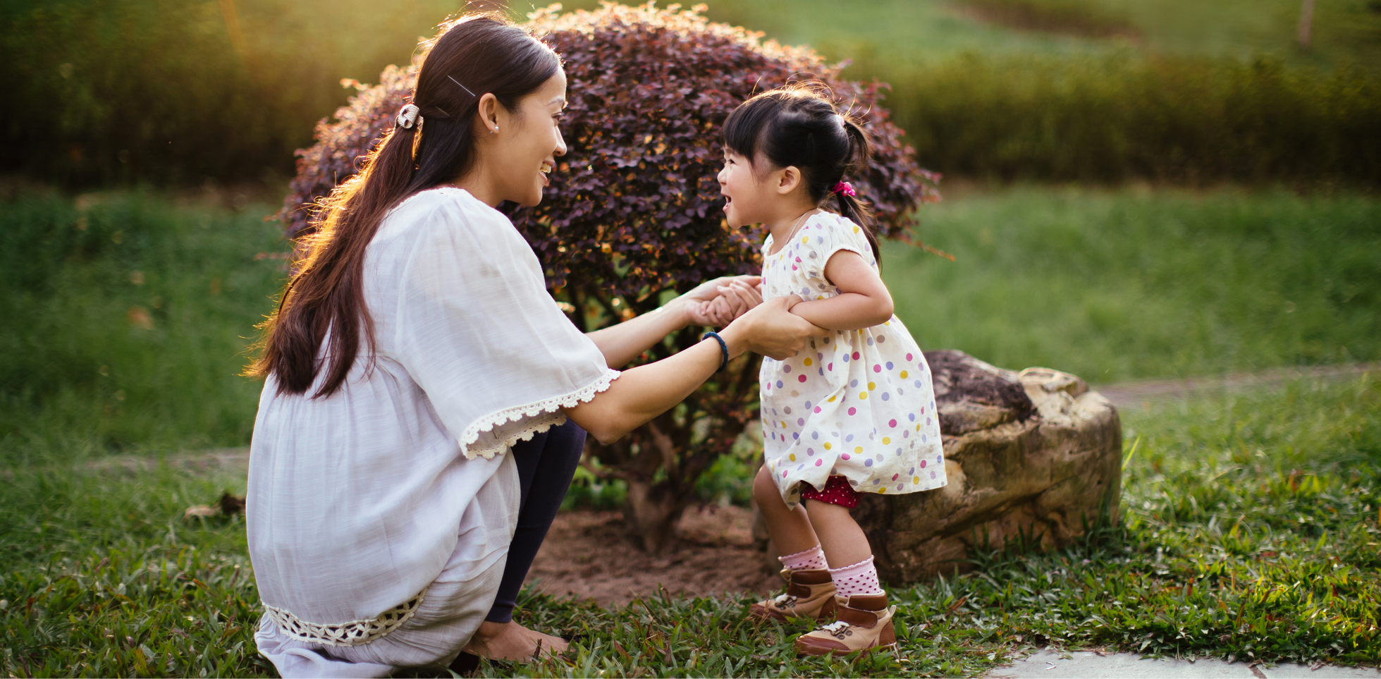 A mother and young child holding hands in the garden